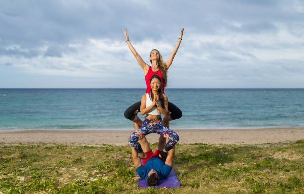 3 человека акробатические позы йоги у моря - yoga challenge for 3 стоковые фото и изображения