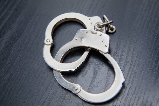istock Silver handcuffs above wooden table 945951156
