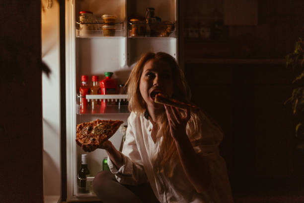 istock Young woman eating pizza late night 945951458