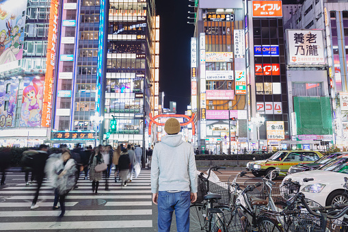 An asian male tourist standing on the night street in Kabukicho, which is one of the most famous entertainment and nightlife districts in Japan.