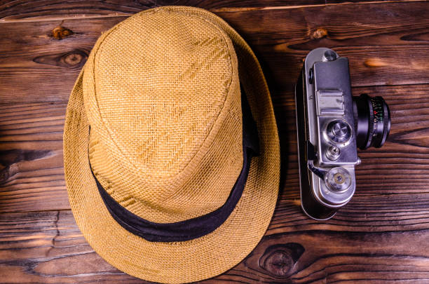 istock Old rangefinder camera and hat on a wooden table. Top view 945958036