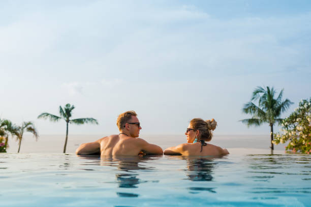 coppia felice in piscina a sfioro - infinity pool foto e immagini stock