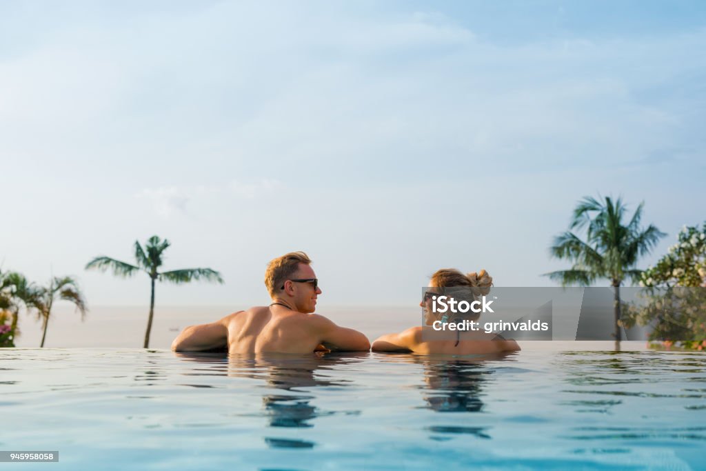 Happy couple in infinity pool Happy couple relaxing in infinity pool Couple - Relationship Stock Photo