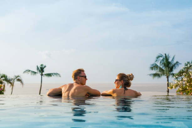 Happy couple in infinity pool Happy couple relaxing in infinity pool infinity pool stock pictures, royalty-free photos & images