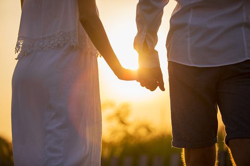 Romantic photo of couple holding hands at sunset