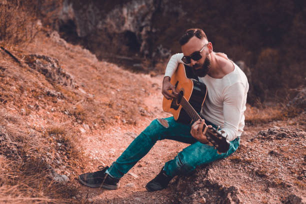 istock Man with a guitar enjoying a beautiful day in nature 945960670
