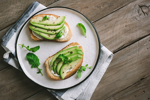 Avocado sandwiches with cream cheese - sliced avocado on toasted bread for healthy breakfast or snack.