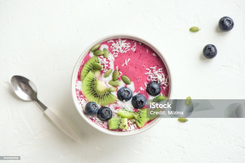 blueberry coconut smoothie bowl Smoothie bowl with fresh berries, fruits, seeds and coconut cream for healthy vegan vegetarian diet breakfast. Acai blueberry coconut smoothie bowl. Bowl Stock Photo