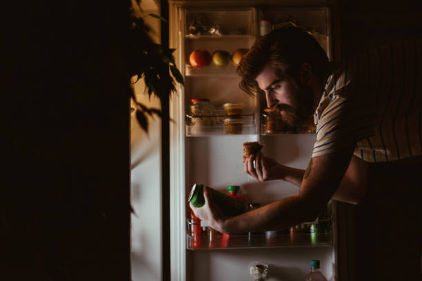 istock Handsome man eating late night and drinking beer 945964226