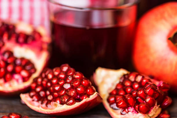 istock Ripe pomegranates with glass of juice on table 945971336