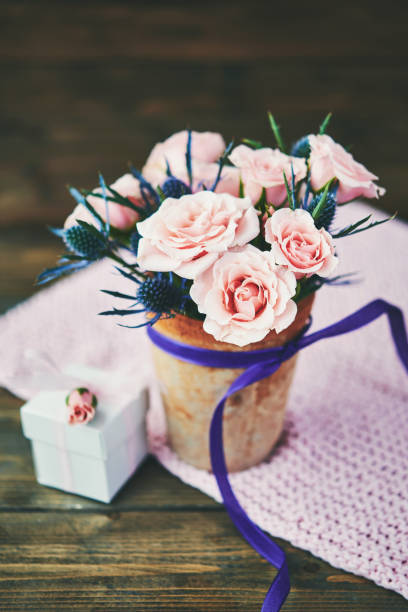 istock Mother's Day bouquet with pink roses and gift in rustic setting 945975322