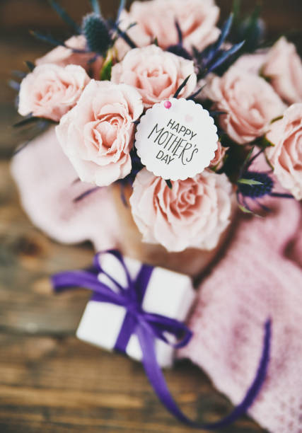 istock Mother's Day bouquet with pink roses and gift in rustic setting 945975450