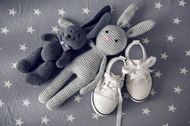 istock two grey knitted toy rabbit and children's white shoes 945981436