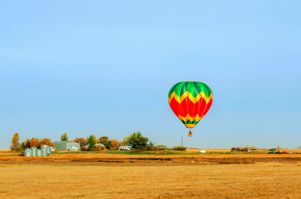 istock A multi-colored balloon is flying over a field in the sky near a farm 945989162