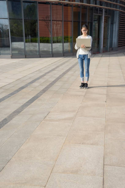 istock young woman using laptop front of office building 945990006