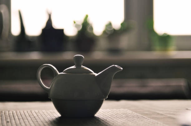 istock White teapot on the table in backlit, selective focus. 945999790