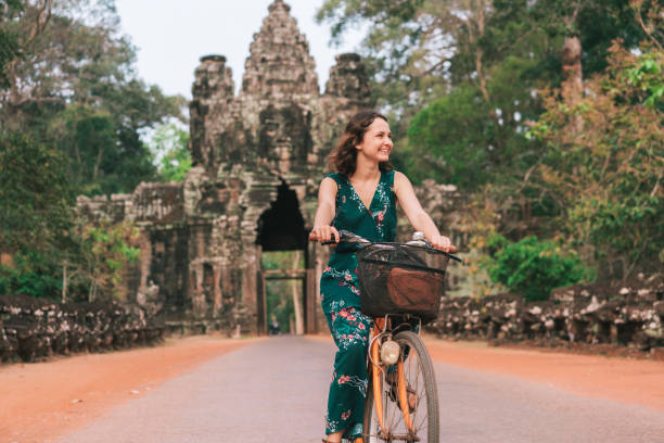 jovem bicicleta de equitação mulher caucasiana em angkor wat - angkor ancient architecture asia - fotografias e filmes do acervo