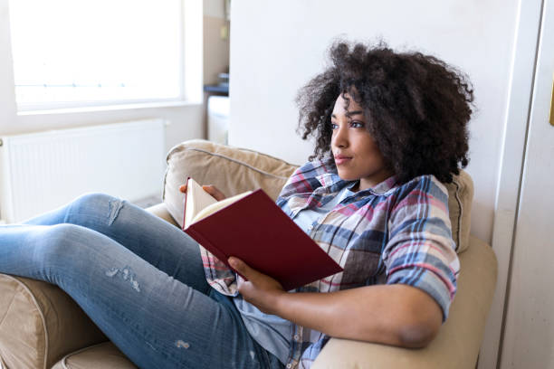 istock Young woman reading a book at home 946024820