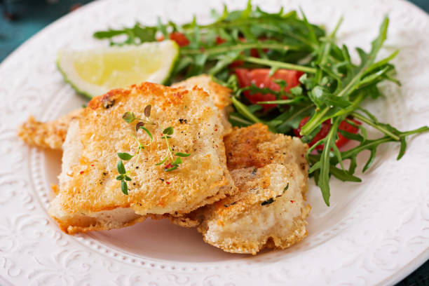 istock Fried white fish fillets and tomato salad with arugula. 946025470