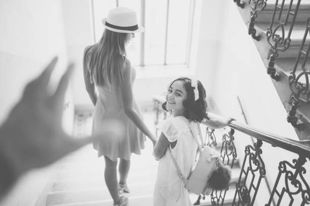 Rear view of mother and daughter going downstairs together