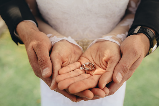 Close up of two wedding rings on bride and groom's palms. Bride and groom holding wedding rings on their palms during ceremony.