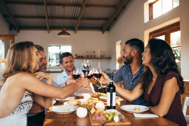 istock Cheerful friends toasting wine at dinner party 946029452