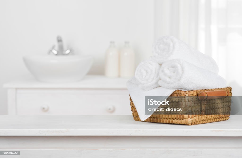 Cesto de toallas en madera mesa con interiores baño borrosa - Foto de stock de Baño libre de derechos