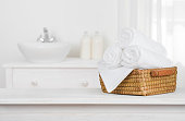 Towels basket on wooden table top with blurred bathroom interior