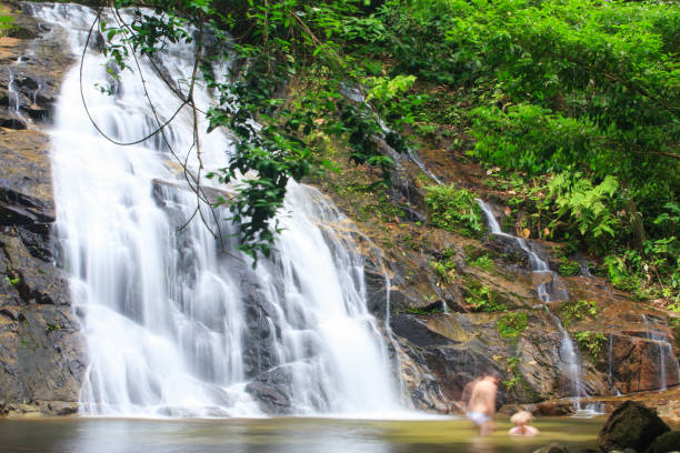 istock Tourist relaxing under flowing waterfall nature. 946035196