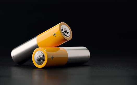 AA size yellow and silver colored  two batteries on black background with selective focus. Horizontal composition with copy space.
