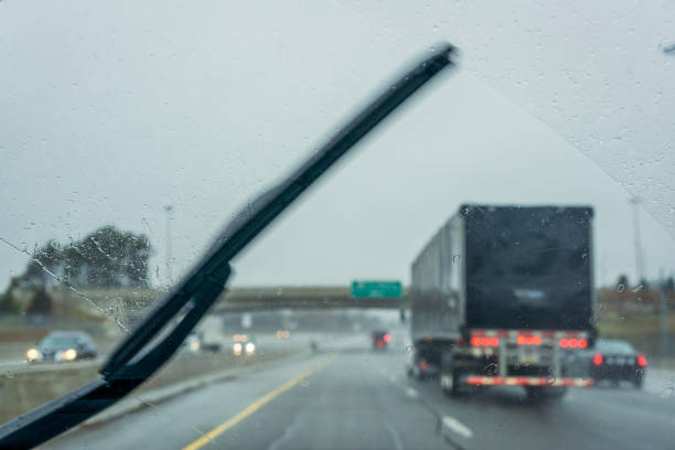 Freeway driving in the rain Motion blur on a windshield wiper as it clears rain during a freeway journey. Focus is on the raindrops on the glass of the windshield. truck rain stock pictures, royalty-free photos & images