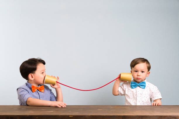 dos niños están usando tazas de papel como un teléfono - 4 string fotografías e imágenes de stock