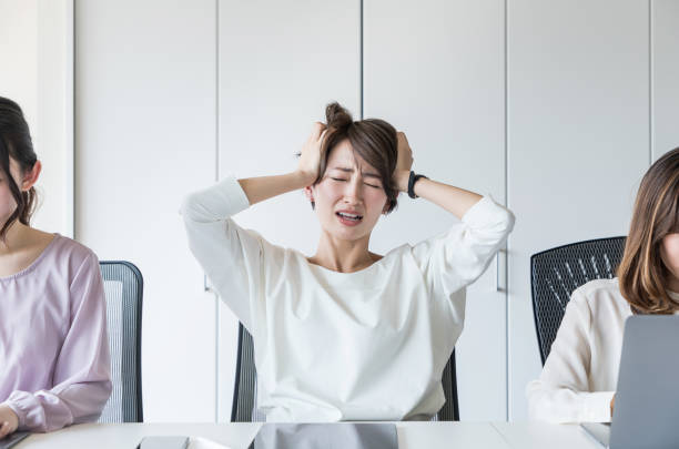 若い女性は彼女の頭を抱えています。 - 仕事ストレス ストックフォトと画像