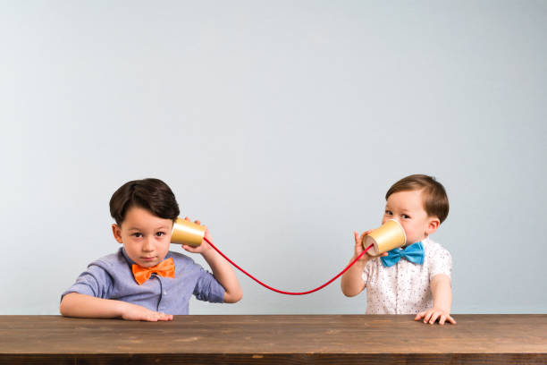 deux childeren se servent des gobelets en papier comme un téléphone - tin can phone photos et images de collection