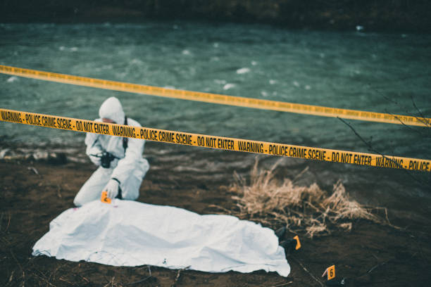 istock Crime investigator with camera kneeling beside a corpse 946040040