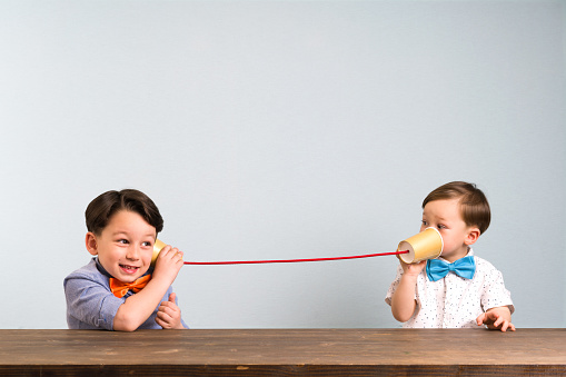 Dos niños están usando tazas de papel como un teléfono photo