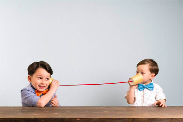 due bambini stanno usando tazze di carta come telefono - udire foto e immagini stock