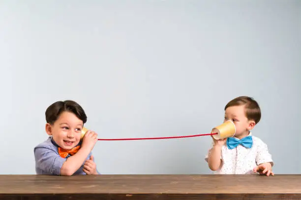 Photo of Two childeren are using paper cups as a telephone