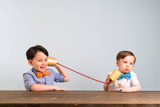 istock Two childeren are using paper cups as a telephone 946040376