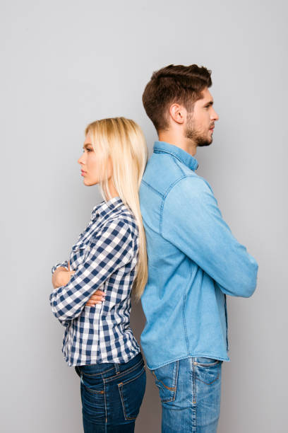 istock Serious man and woman with crossed hands standing back to back 946042802