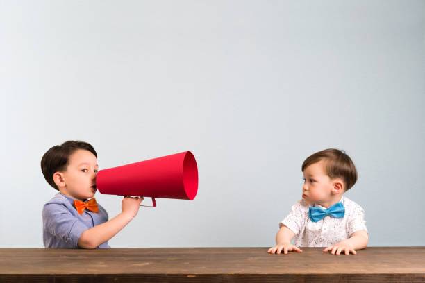 istock Child is shouting through megaphone to another child 946043100