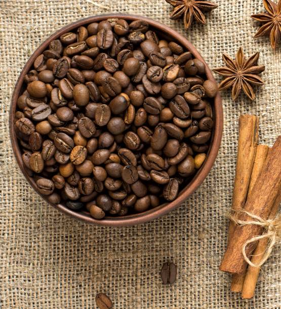 istock Cinnamon, star anise and coffee beans in a barrel on a burlap napkin. Top view 946043270