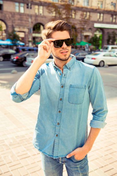 istock stylish young man walk  and hold his glasses 946043474