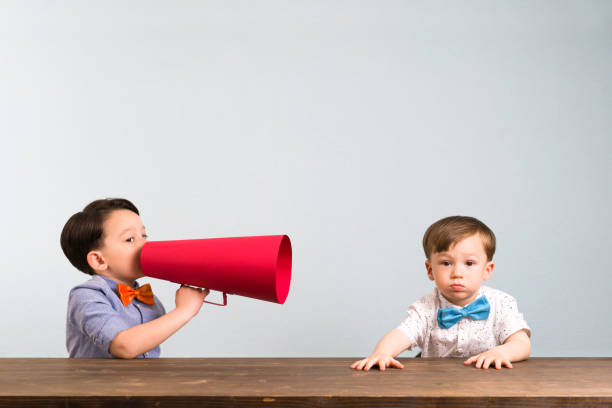 istock Child is shouting through megaphone to another child 946043744