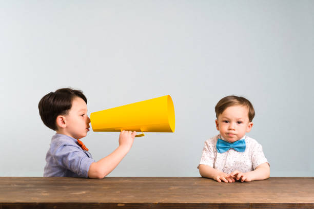 istock Child is shouting through megaphone to another child 946047028