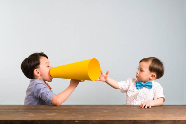 istock Child is shouting through megaphone to another child 946047030