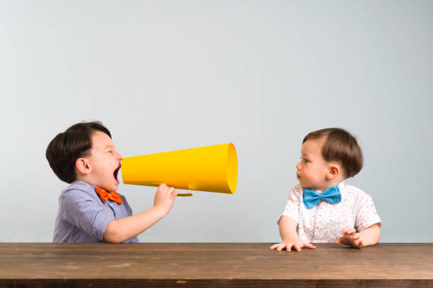 istock Child is shouting through megaphone to another child 946047034