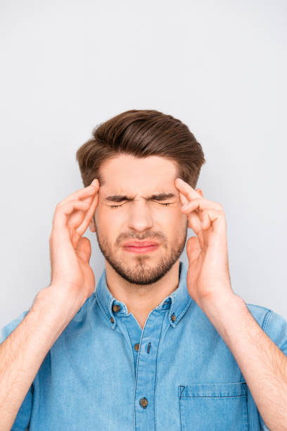 istock Handsome young tired man with migraine touching head 946051538