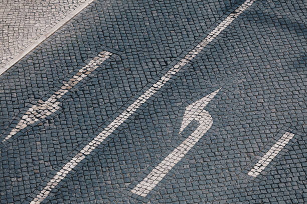 Direction arrow and street sign on handmade stone pavement in Lisbon - Traditional Portuguese handmade mosaic background - Cobble stone street