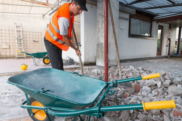Reconstruction of waterproofing and insulation of a roof - terrace. Phase of excavation and preparation of the fund. Worker collects the rubble Home repair. Removal of debris, concrete blocks and bricks from the bottom of a roof - terrace. Worker with orange reflective jacket and shovel in his hand wheelbarrow stock pictures, royalty-free photos & images